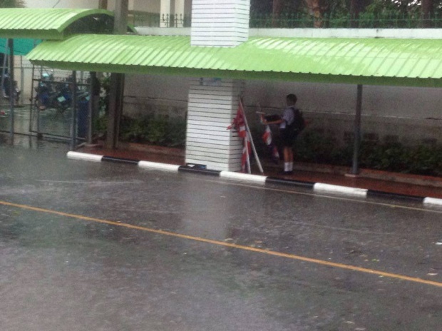 ภาพน่าชื่นชม หนุ่มน้อยในชุดนักเรียน วิ่งฝ่าสายฝนเก็บธงชาติกลางถนน